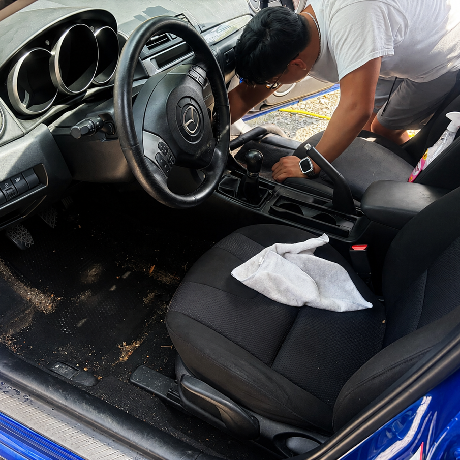 Car interior being professionally detailed with clean dashboard, vacuumed seats and spotless surfaces
